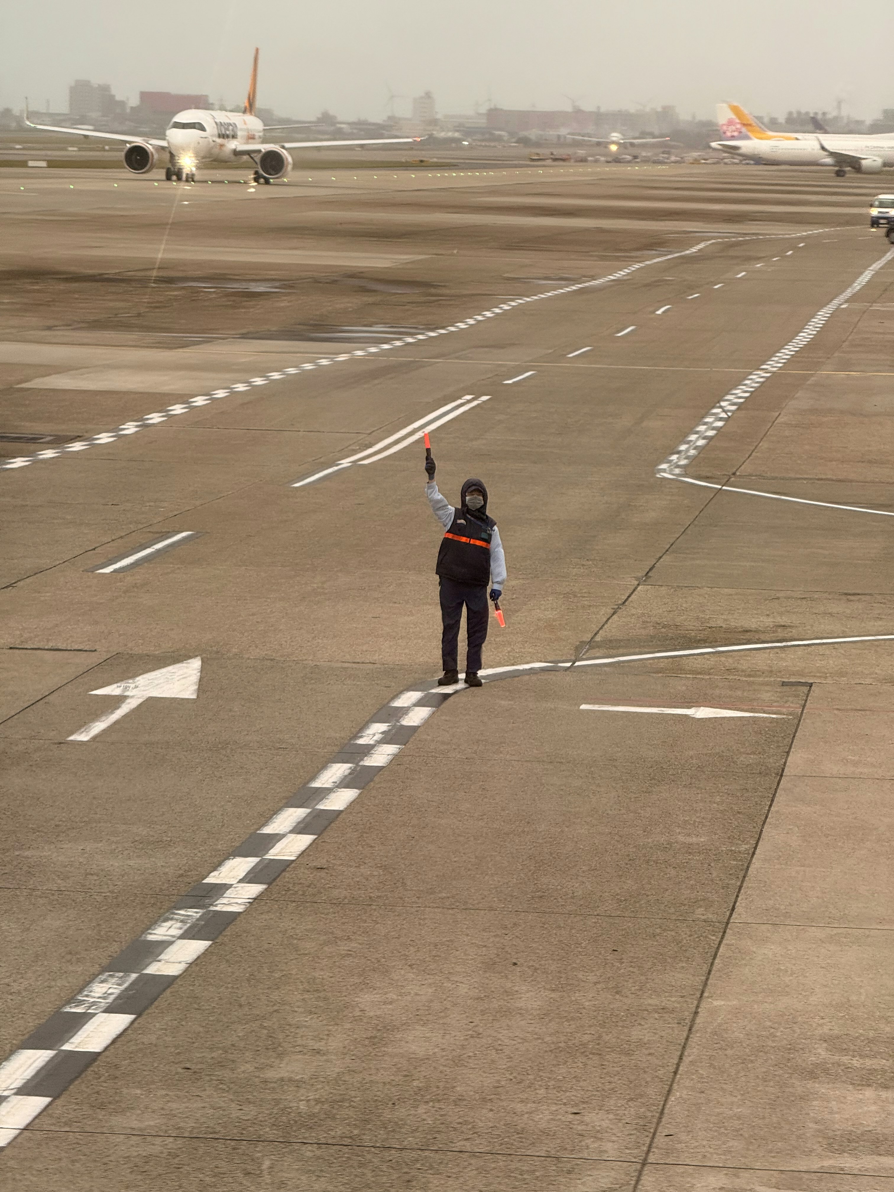 Airport ground worker directing aircraft movements on an active apron